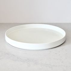 a white plate sitting on top of a marble counter next to a black and white cat