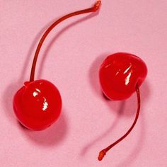 two red cherries on a pink surface