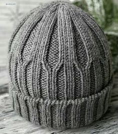 a gray knitted hat sitting on top of a wooden table next to a plant