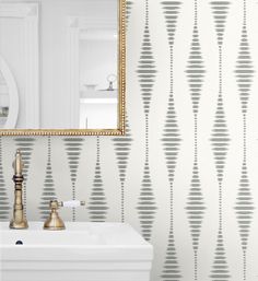 a white sink sitting under a mirror next to a wall mounted faucet in a bathroom