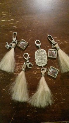 six charms with tassels and pictures on them sitting on top of a wooden table