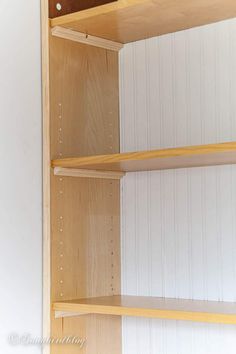 two wooden shelves with white paint on the wall and one shelf has an open door