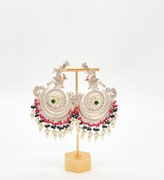 Upgrade your festive look with silver-coated pachi kundan peacock earrings featuring tribal designs and pearl tassels. Earrings Length: Approx. 4" Weight of each earring: 25 gms Brass as the base metal Availability: In-Stock *Color may vary slightly due to light condition & photography. Jewelry Care: Keep away from moisture. Allow perfumes and lotion to dry before wearing. Store in jewelry pouch. Clean only with soft lint free cloth.