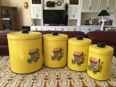 three yellow canisters with designs on them sitting on a table in front of a couch