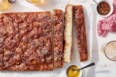 two pieces of bread sitting on top of a cutting board next to dipping sauces