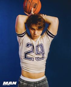 a young man holding a basketball over his head with both hands on top of his head