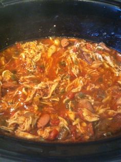 a slow cooker filled with pasta and meat in tomato sauce on the stove top