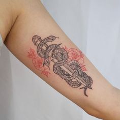 a woman's arm with a snake and dagger tattoo on it