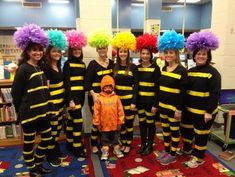 a group of people in bee costumes posing for a photo with a child on the floor