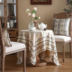 a table with two chairs and a vase filled with white flowers on top of it