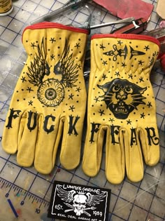 two pairs of yellow leather gloves sitting on top of a table next to scissors and pliers