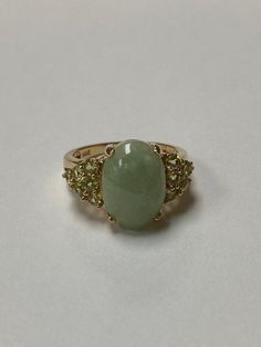 Lady's 14 karat yellow gold ring, with a large oval green jadeite jade at the center and accented by 12 round full cut natural peridot gemstones. The jade measures 14.0 mm x 10.0 mm with a depth of 4.65mm. The 12 round peridot measure approximately 2.5mm each. The ring is a size 8 and can be sized up or down. The ring weighs 4.72 grams. The ring is from an estate here in Hawai'i. The item is C11870/2 Please let me know if you have an questions. Mahalo for looking at my item. Elegant Green Emerald Ring With Stones, Luxury Green Oval Gemstones, Oval Green Cabochon Gemstones, Green Multi-stone Oval Cabochon Jewelry, Oval Multi-stone Emerald Ring, Green Oval Rings With Stones, Green Oval Cabochon Ring With Accent Stones, Oval Green Rings With Stones, Green Oval Multi-stone Gemstones