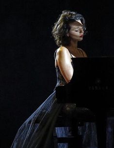 a woman in black dress sitting at a piano