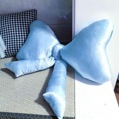 a blue bow pillow sitting on top of a bed next to two black and white pillows