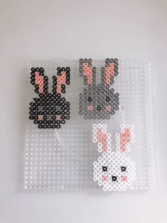 the bead art is designed to look like two rabbits and one bunny with pink ears