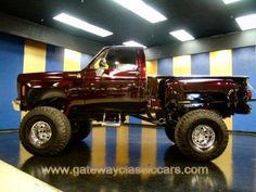 a large red truck parked inside of a garage next to a yellow and blue wall