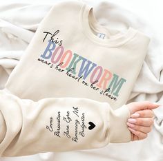 Bookworm Shirt, Bookish Shirt, Book Shirt, Book Sweatshirt, Librarian Gift, Book Lover Shirt, Gift for Reader, Reading Shirt, Banned Books Shirt, This Bookworm Wears her Heart on her Sleeve, Reading Shirt, Reading Sweatshirt, Bookish Tee, Book Nerd Shirt, Bookish Sweater, One More Chapter. Our sweatshirts and hoodies are available in various colors.  The actual color may slightly vary due to different lightings.  For Sweatshirt, we use Gildan Heavy Blend Crewneck Sweatshirt. Material is 60% Polyester and 40% Cotton. For Hooded Sweatshirt, we use Heavy Blend Adult Hooded Sweatshirt. Material is 50% Cotton and 50% Polyester. Please select the size and color before adding it to the cart. Please check the Size Chart in the pictures to choose the correct size. Return Policy No Return Accepted. Book Lover Shirt, Book Shirt Ideas, Bookish Tees, Random Trinkets, Reading Sweatshirt, Book Nerd Shirts, Nerd Shirt, Books Shirt, Bookworm Shirt