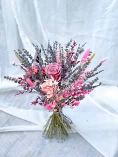 a vase filled with lots of pink flowers on top of a white cloth covered table