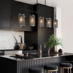 a modern kitchen with black cabinets and gold accents, including an island bar stools