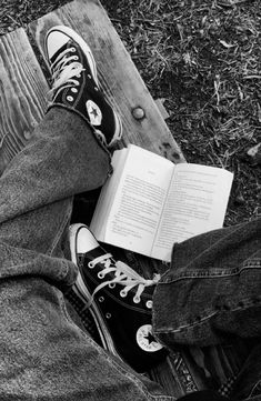 black and white photo of person with book on the ground in front of their feet