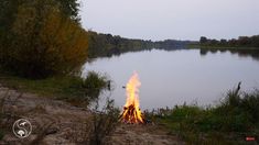 there is a fire burning in the middle of the water and grass on the shore