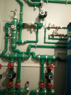 green pipes and valves are connected to the wall in this room with no one around them