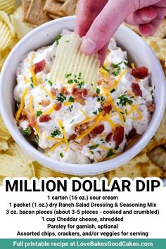 a hand dipping a chip into a bowl of potato salad with bacon and cheese on top