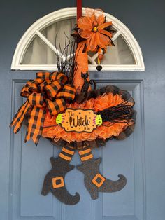 an orange and black wreath with the word witch hanging on a blue front door decorated for halloween