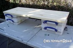 two plastic storage containers sitting on top of a white picnic table with blue handlebars