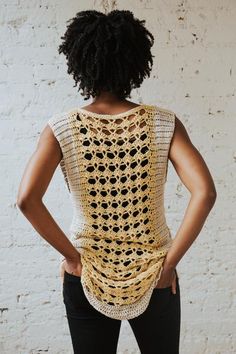 a woman standing with her back turned to the camera, wearing a crochet top