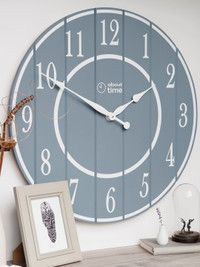 a large clock on the wall next to a framed photograph and vase with an ornament