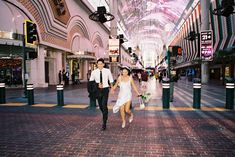 a man and woman walking down a street next to each other in a shopping mall