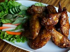 some chicken wings are sitting on a plate next to a salad and lettuce