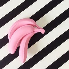 a pink banana sitting on top of a black and white striped table