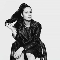 a black and white photo of a woman in a wheelchair with her hair blowing back