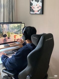 a man sitting at a desk with headphones on and looking at a computer screen