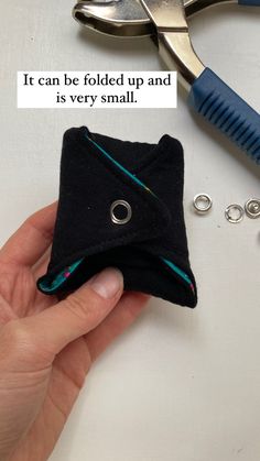 a person holding a small black piece of fabric next to some scissors and other items