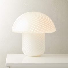 a white mushroom lamp sitting on top of a table next to a wall mounted clock