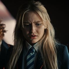 a woman with long blonde hair wearing a suit and tie