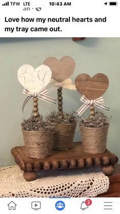 two wooden hearts are sitting on top of some straw and twine in small pots