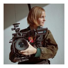 a woman holding a camera in her hand and looking at the camera on top of it