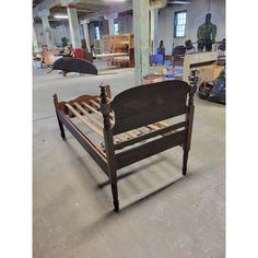 a wooden bench sitting in the middle of a warehouse filled with furniture and other items