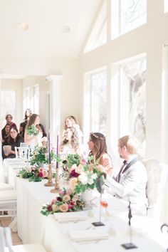 the bride and grooms are sitting at the long table