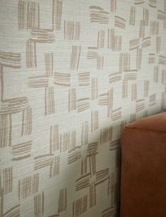 a brown chair sitting in front of a wall with a pattern on it's side