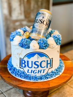 a cake decorated with blue and white frosting, topped with a bottle of busch light