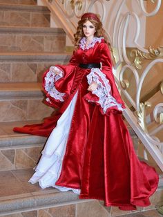 a doll dressed in a red and white gown standing on some stairs with her hand on her hip