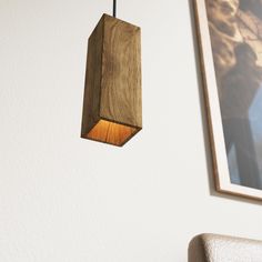 a wooden light fixture hanging from a wall next to a painting on a white wall