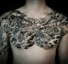 a man's chest covered in tattoos with dragon and flowers on the chest area