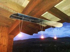 an upside down snowboard hanging from a wooden structure with lights in the dark below