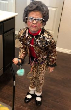 an old woman in glasses and leopard print outfit standing next to a black crutch